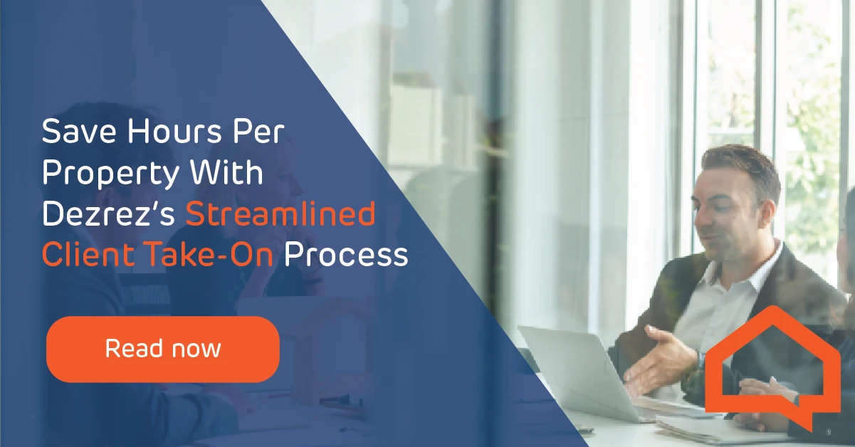 A business man sat at a table working from his laptop talking to other people at the table