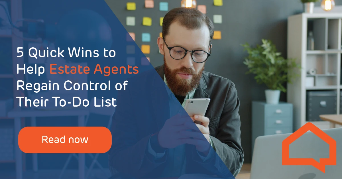 A man is sat at a desk looking happily at his mobile device